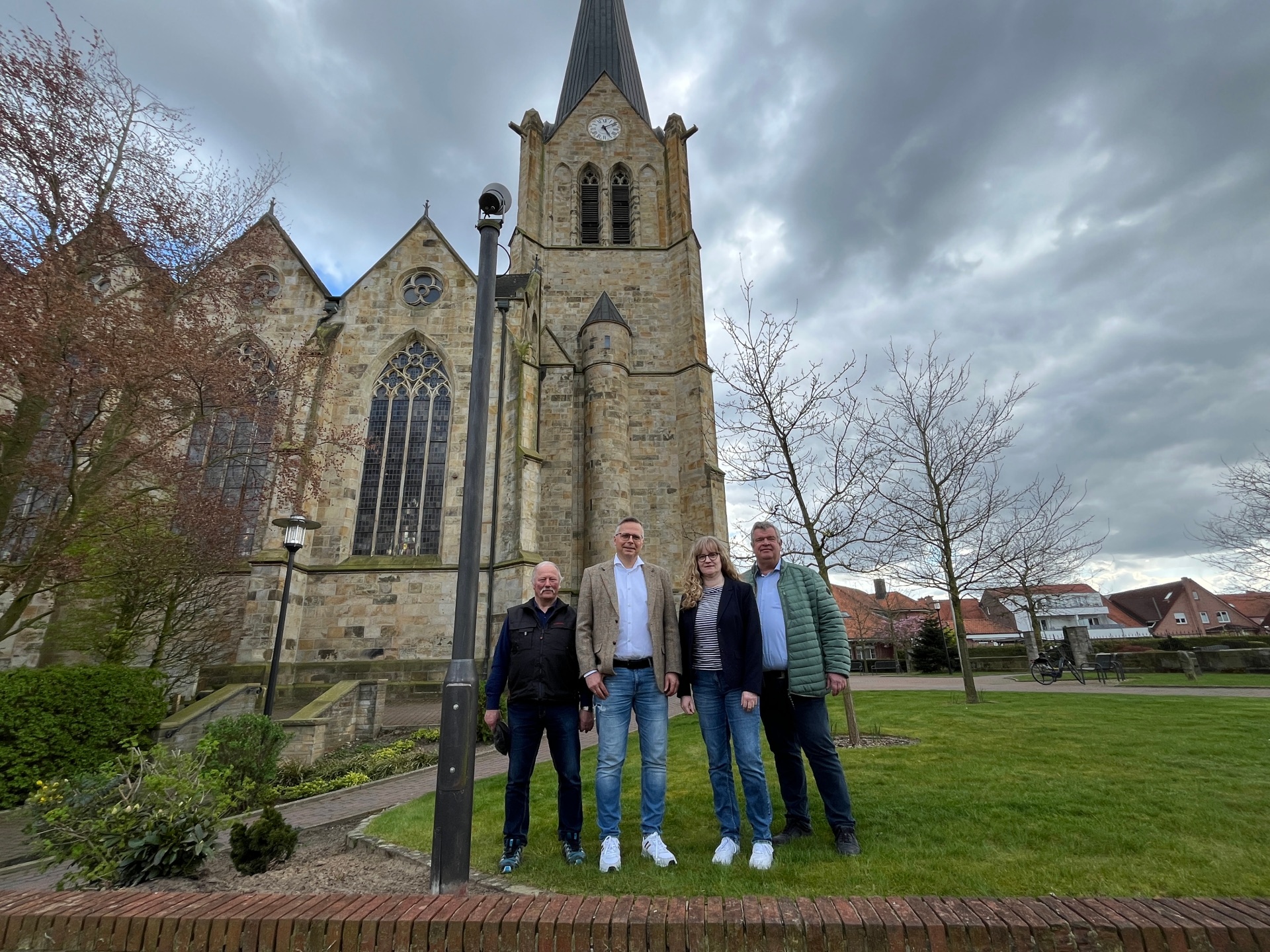 Gerd Schäfer, Ralph Stassen, Sandra Schnetlage und Gerd Wübbe stehen neben dem neuen Strahler an der katholischen Kirche St. Benedikt in Lengerich