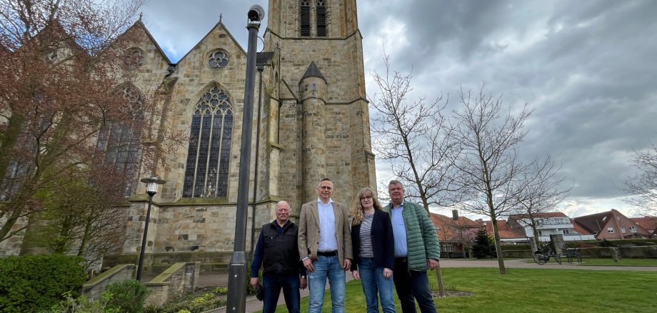 Gerd Schäfer, Ralph Stassen, Sandra Schnetlage und Gerd Wübbe stehen neben dem neuen Strahler an der katholischen Kirche St. Benedikt in Lengerich