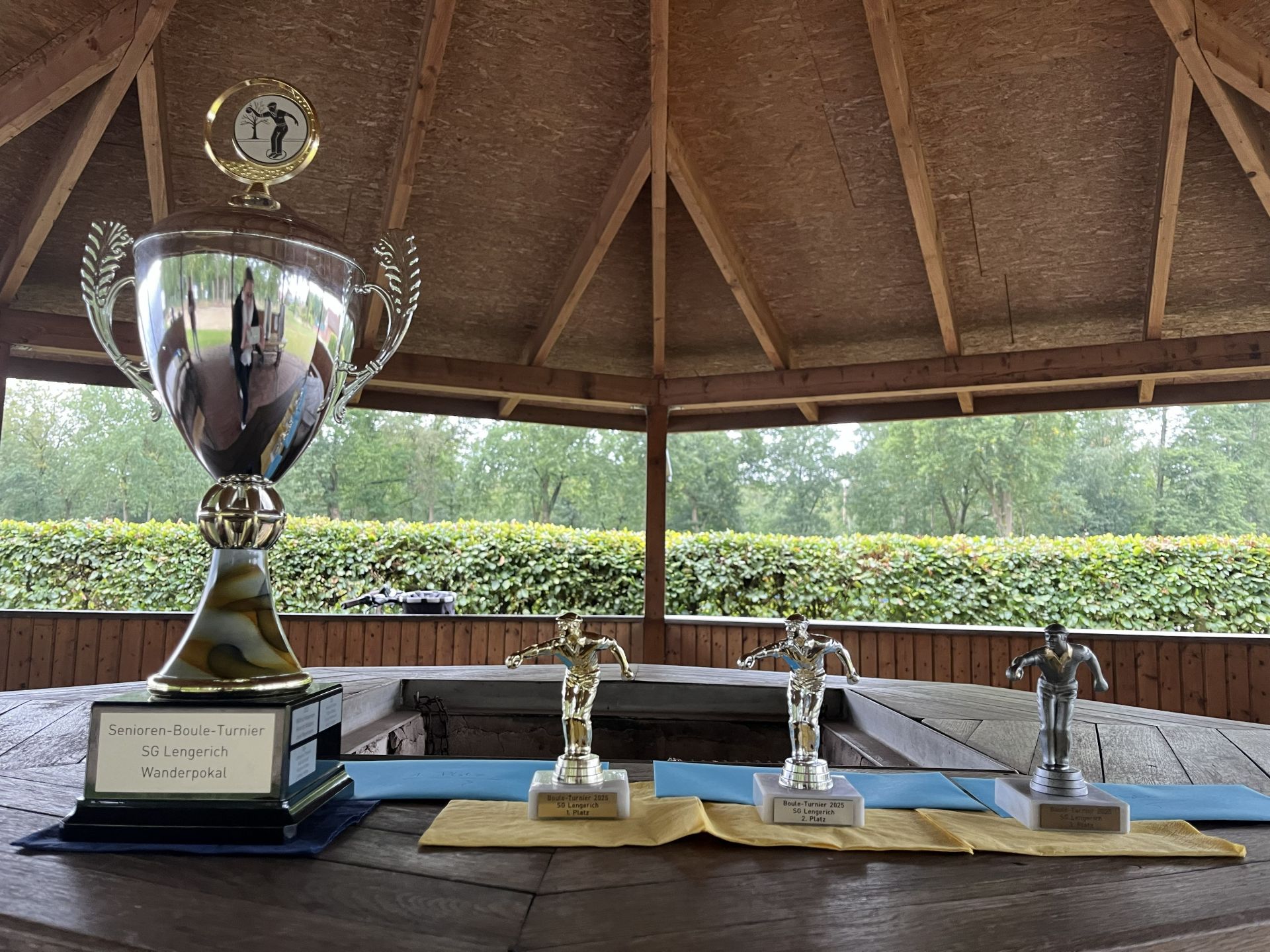 Zu sehen sind der Wanderpokal und 3 kleine Pokale (Gold, Silber und Bronze)