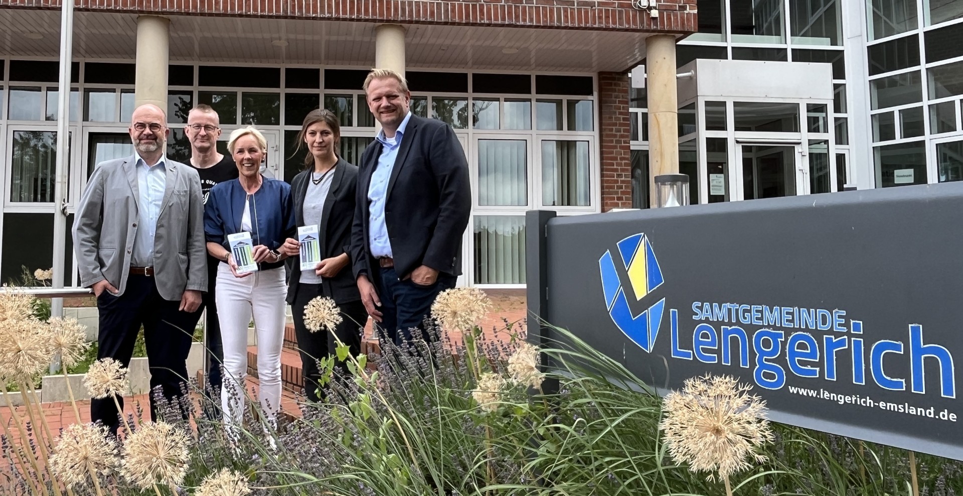 Christoph Schwerdt und Lisa Krieger (genial eG), Samtgemeindebürgermeister Matthias Lühn und Fachbereichsleiter Ansgar Kötting von der Samtgemeinde Lengerich sowie Melanie Schulten vom Landkreis Emsland stehen vor dem Rathaus der Samtgemeinde Lengerich