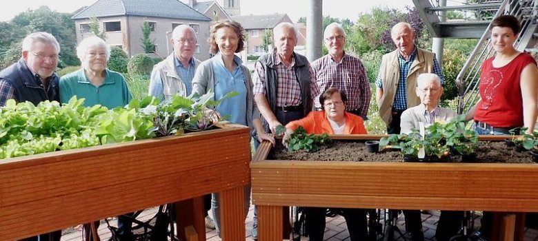 Die Gruppe Tatort Dorfmitte mit Bewohnern und der Leiterin vom Maria Anna Haus an den mobilen Hochbeeten